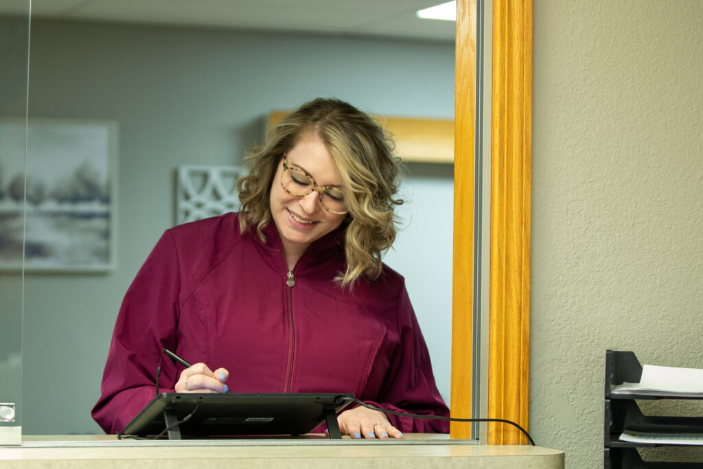 patient completing patient registration form at the front desk of Associated Oral & Implant Surgeons