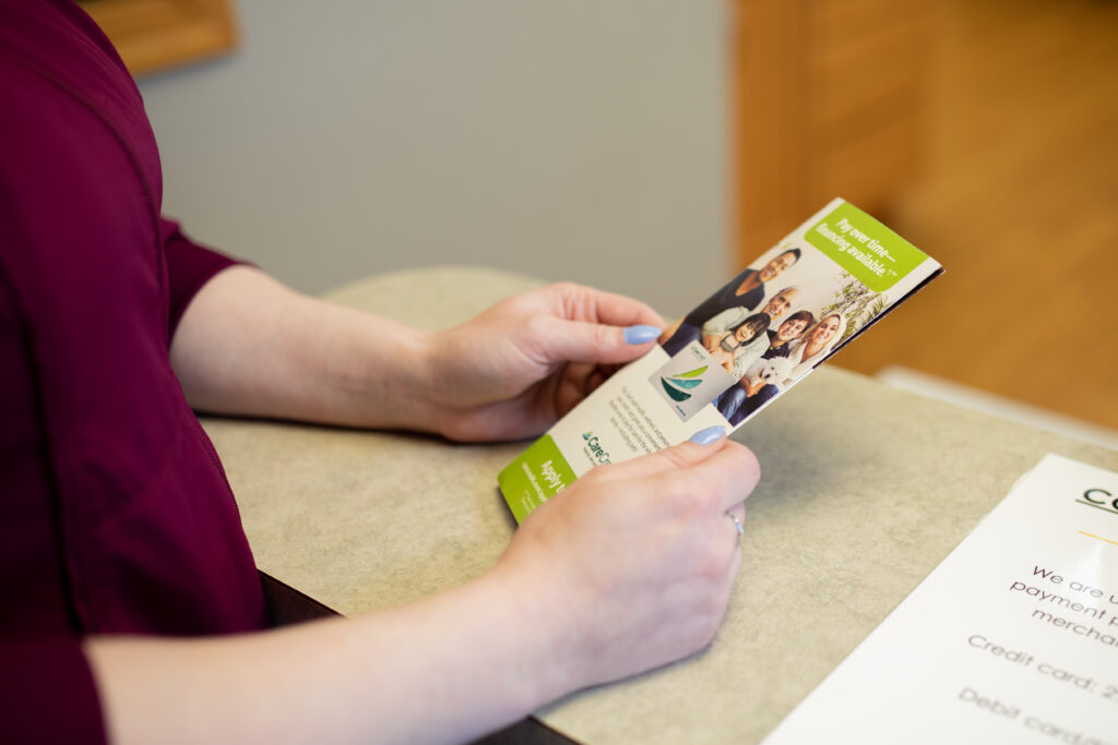 patient looking at a brochure that explains dental insurance and financing options, reasons why people choose our practice at Associated Oral & Implant Surgeons