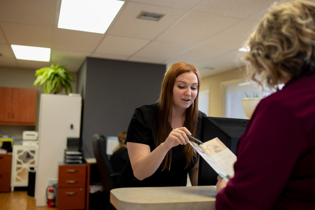 administrative personnel reviewing patient information, health and insurance policies with a patient before receiving dental care at Associated Oral & Implant Surgeons