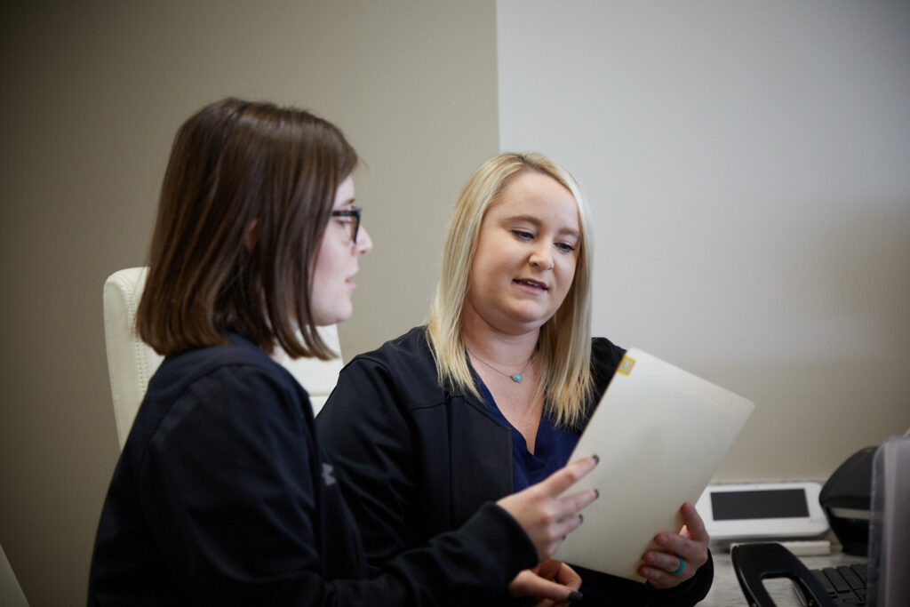 2 Surgical assistants looking over paperwork at Associated Oral & Implant Surgeons