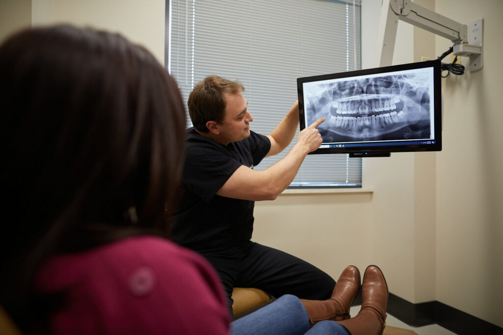 An oral surgeon showing a patient her impacted teeth on an x-ray at Associated Oral & Implant Surgeons