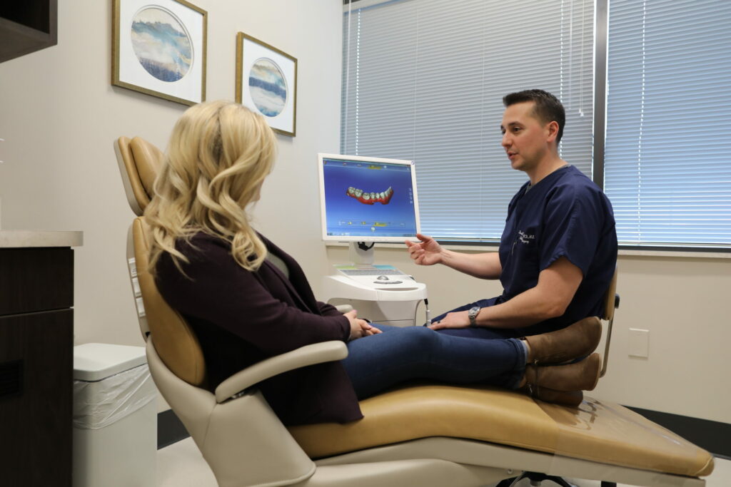 An oral and maxillofacial surgeon talks with a new patient about her dental care options and oral surgery post operative instructions during her first appointment at Associated Oral & Implant Surgeons