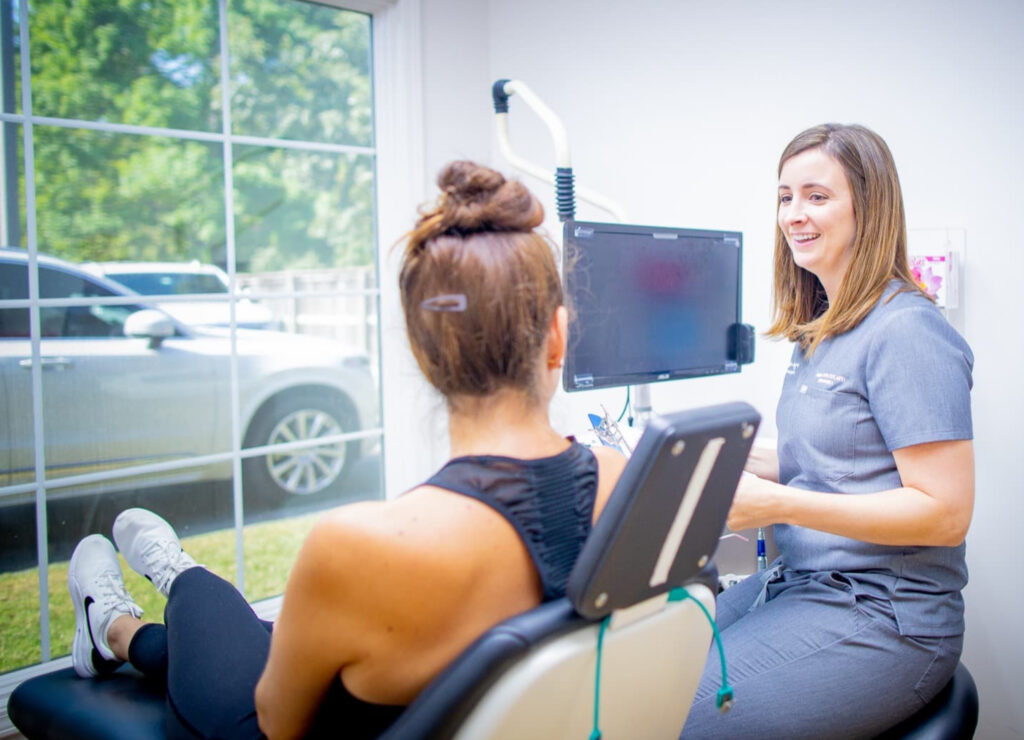 patient in dental chair chatting with dental surgical assistant about oral surgery post operative instructions at Associated Oral & Implant Surgeons