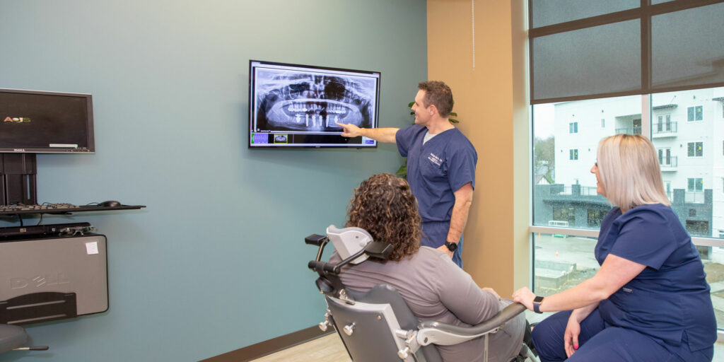 An oral and maxillofacial surgeon and assistant explaining an oral surgery option to a new patient during an initial consultation at Associated Oral & Implant Surgeons