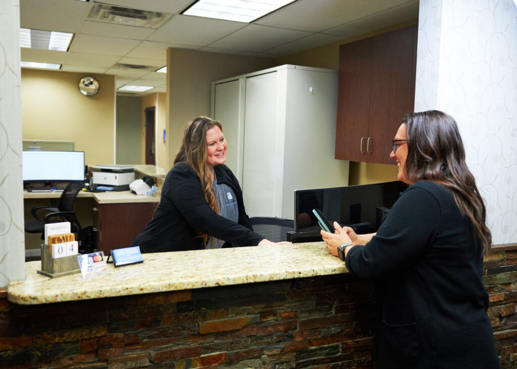 office staff welcoming a new patient for her first visit and explaining financial options and the financial policy for dental care at Associated Oral and Implant Surgeons